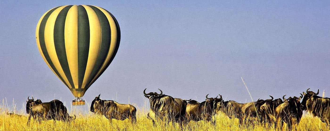 A hot air balloon drifting low over the plains at dawn